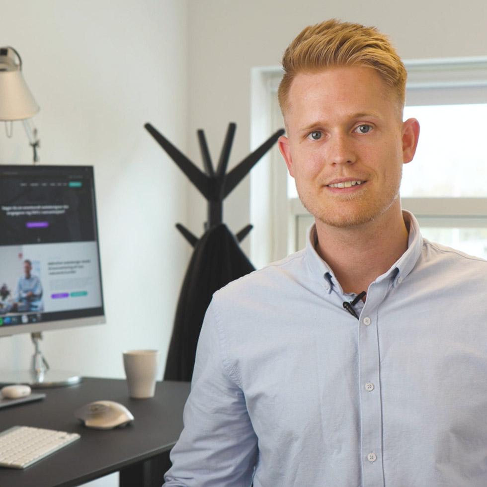 Nicolai Sørensen på kontoret foran en skærm med et webdesignprojekt